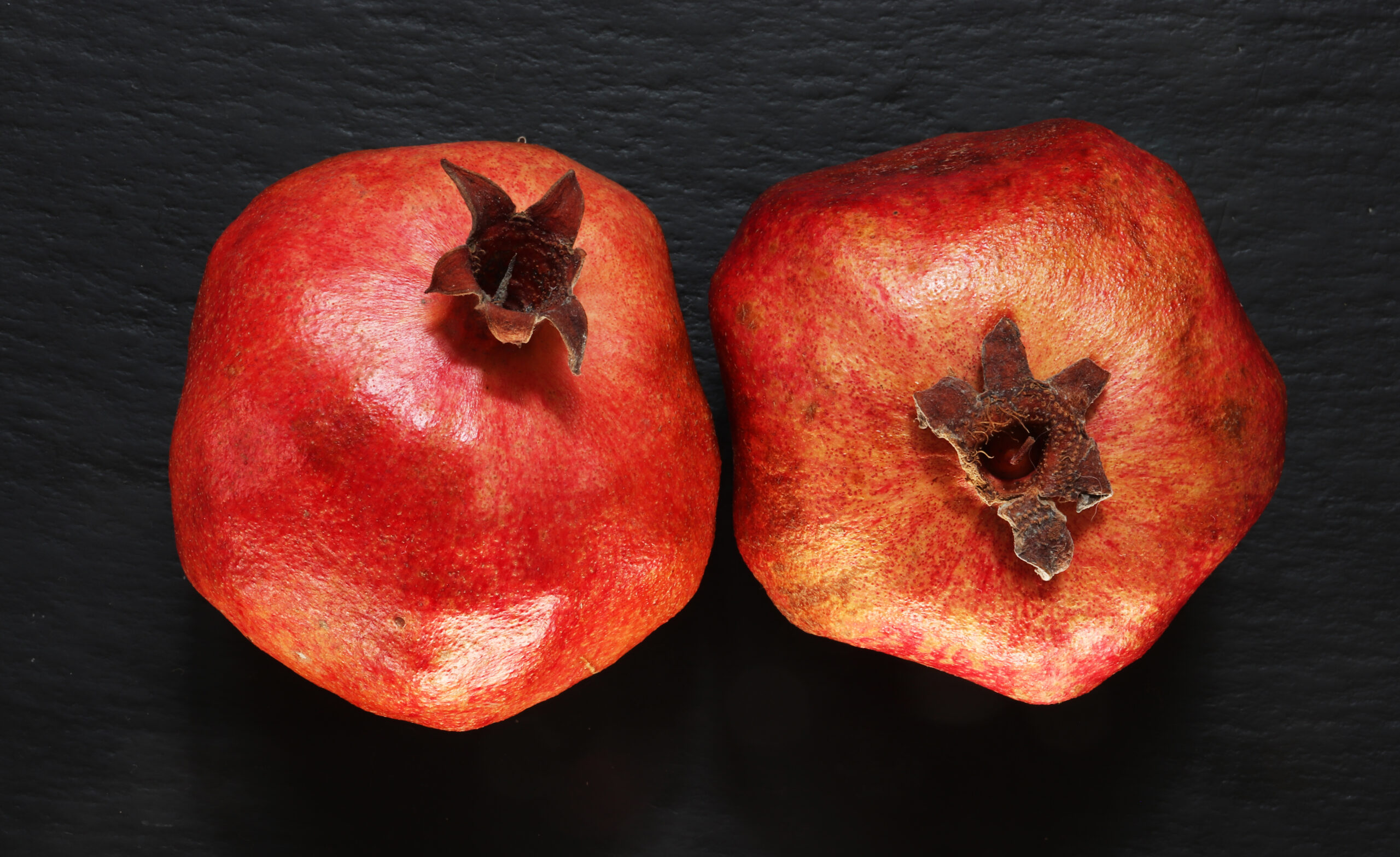 Photography of two whole pomegranates on slate background for fo